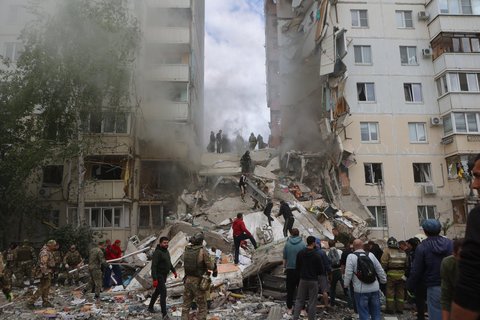 Des pompiers et des volontaires sécurisent la zone sur le site d'un immeuble d'habitation partiellement effondré qui a été endommagé par une frappe ukrainienne à Belgorod, le 12 mai 2024. 